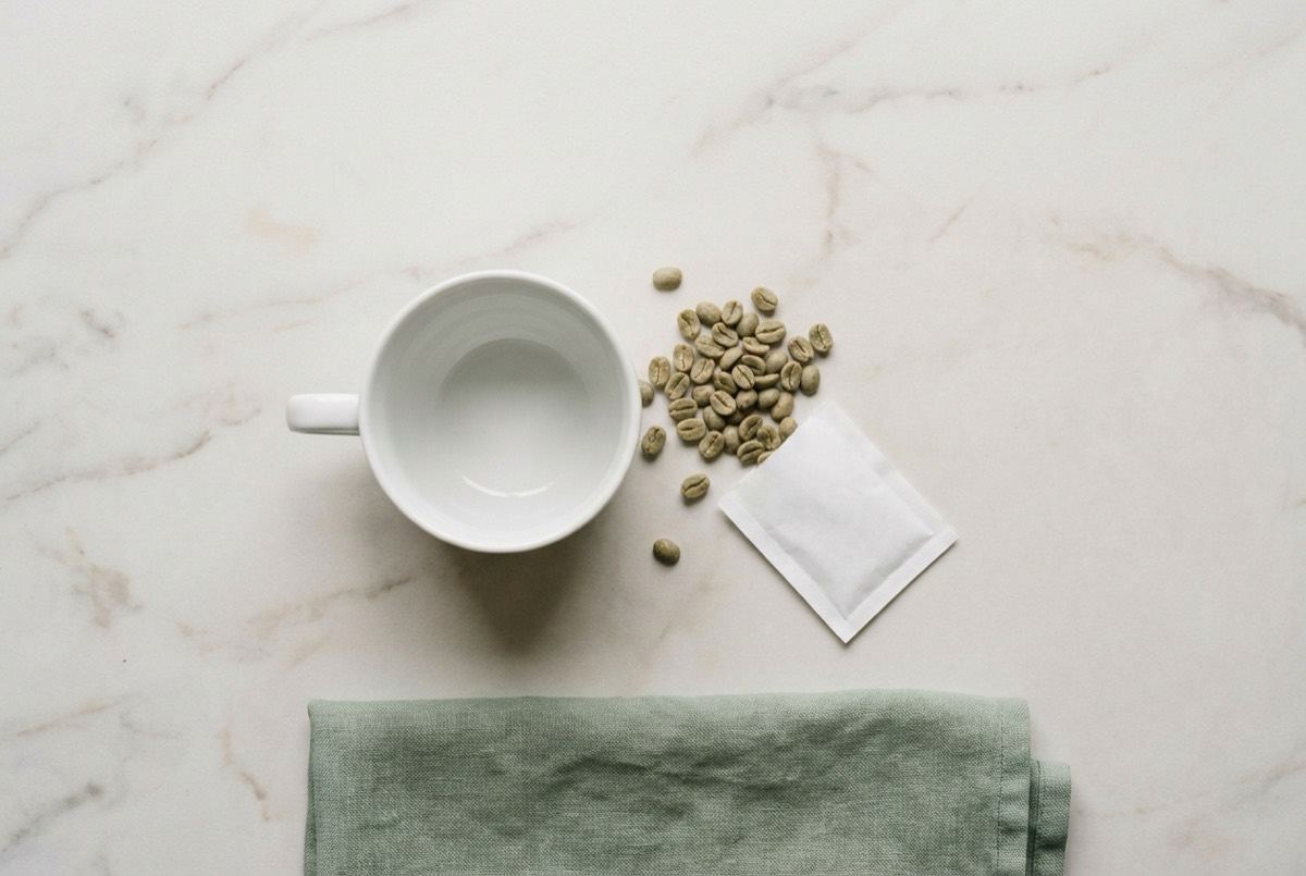 Kaffeetasse mit grünen Kaffeebohnen und Wirkstoff-Päckchen